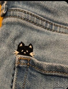 a small black and white cat sticking out of the back pocket of a pair of jeans