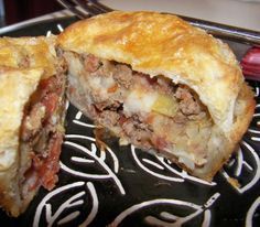 a meat and cheese pie cut in half on a black plate with a red fork