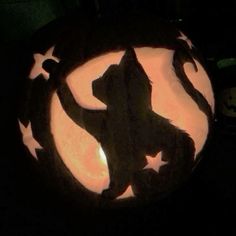 a carved pumpkin with a silhouette of a cat on it's face and stars