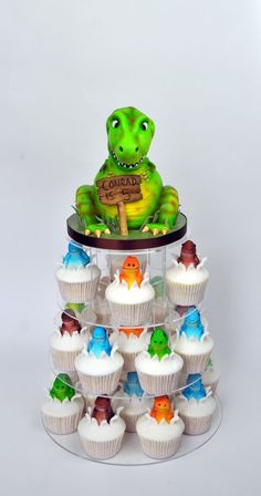 cupcakes are arranged in the shape of a dinosaur on top of a cake stand