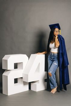 a woman in graduation cap and gown leaning on the letters