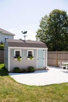 a backyard with a shed, table and chairs