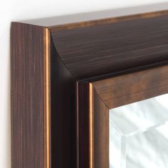 a close up of a mirror on a wall with a wooden frame and wood grained finish