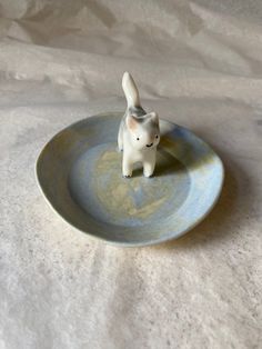 a small white dog figurine sitting on top of a blue and gray plate