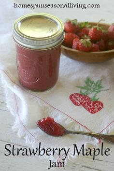 a jar of strawberry maple jam next to a bowl of strawberries on a table