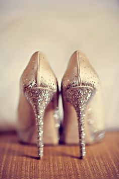 a pair of high heeled shoes sitting on top of a wooden table next to a sign