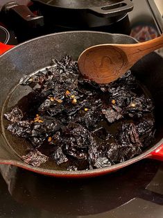 a pan filled with food sitting on top of a stove next to a wooden spoon