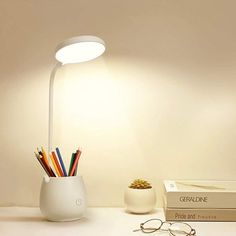 a desk with a lamp, books and glasses on it next to a pair of eyeglasses