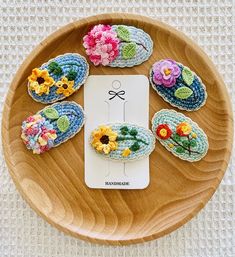 crocheted slippers with flowers are arranged on a wooden plate next to an electronic device