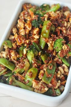 a white dish filled with broccoli and nuts