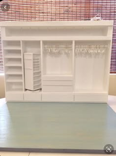 a white doll house with shelves and drawers