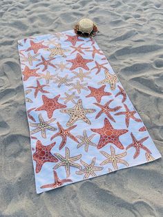 a beach towel with starfishs on it laying in the sand