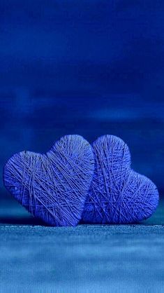 two balls of yarn sitting on top of each other in front of a blue background