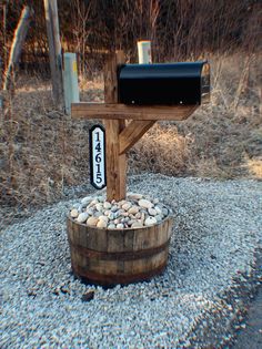 a mailbox sitting on top of a wooden barrel filled with rocks