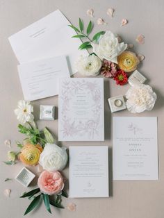 the wedding stationery is laid out with flowers