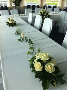 the table is set with white flowers and greenery