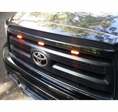 the front end of a black car with lights on it's grille and hood