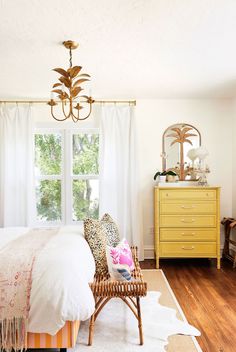 a bedroom with yellow furniture and white curtains