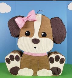 a brown and white dog with a pink bow on its head sitting in front of a blue background