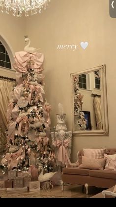 a decorated christmas tree in a living room with pink and white decorations on the top