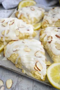 lemon almond scones on a baking sheet with sliced lemons and almonds in the background