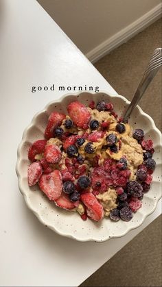 a bowl of oatmeal with strawberries and blueberries in it on a table