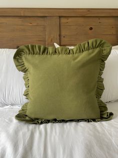 a green pillow sitting on top of a white bed