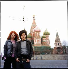 two people standing next to each other in front of a building with domes on it