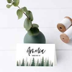 a place card with trees on it next to a spool of twine