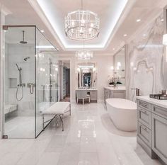 a large bathroom with a chandelier and white marble walls, along with an oval bathtub