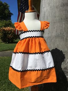 an orange and white dress is on display in front of a tree with the american flag behind it