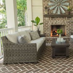 a living room filled with furniture and a fire place in front of a brick wall