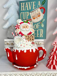 there is a red teapot with santa clause in it and candy canes on the table