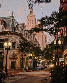 a city street filled with lots of traffic and tall buildings covered in lights at dusk