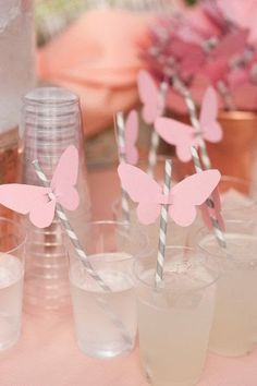 pink butterfly straws in plastic cups on a table