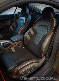 the interior of a sports car with black leather and orange stitching on the seats