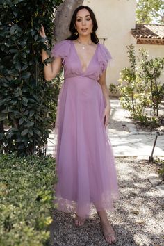 a woman in a purple dress posing for the camera