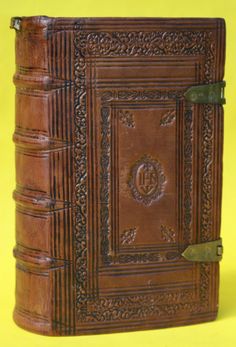 an old leather book with intricate carvings on the front and sides, sitting against a yellow background