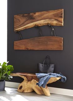 a wooden bench sitting in front of a black wall next to a potted plant