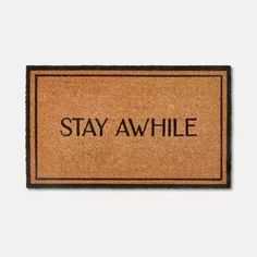 a door mat with the words stay awhile on it in black lettering, against a white background