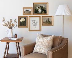 a living room with pictures on the wall and a chair in front of a lamp