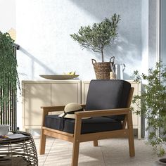 a wooden chair sitting on top of a tile floor next to a potted plant