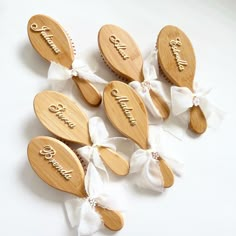 six wooden spoons with names on them and bows tied around the handles are arranged in rows