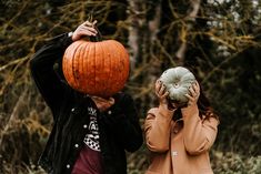 two people holding up pumpkins in front of their faces