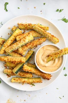 fried zucchini sticks with dipping sauce on a white plate