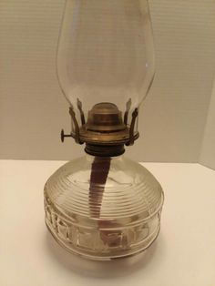 an antique glass and brass oil lamp on a white table top with a brown ribbon around it