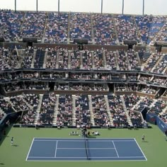 an aerial view of a tennis court with many people in the stands and one player on the court