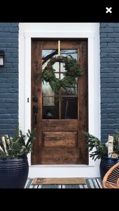 the front door is decorated with wreaths and potted plants