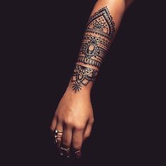 a woman's arm with a henna tattoo on her left hand and an intricate design on the wrist