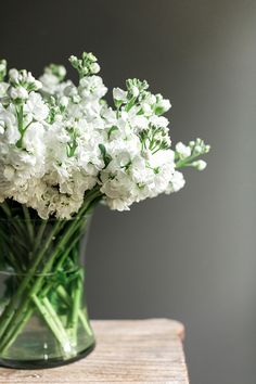 a glass vase filled with white flowers on top of a table